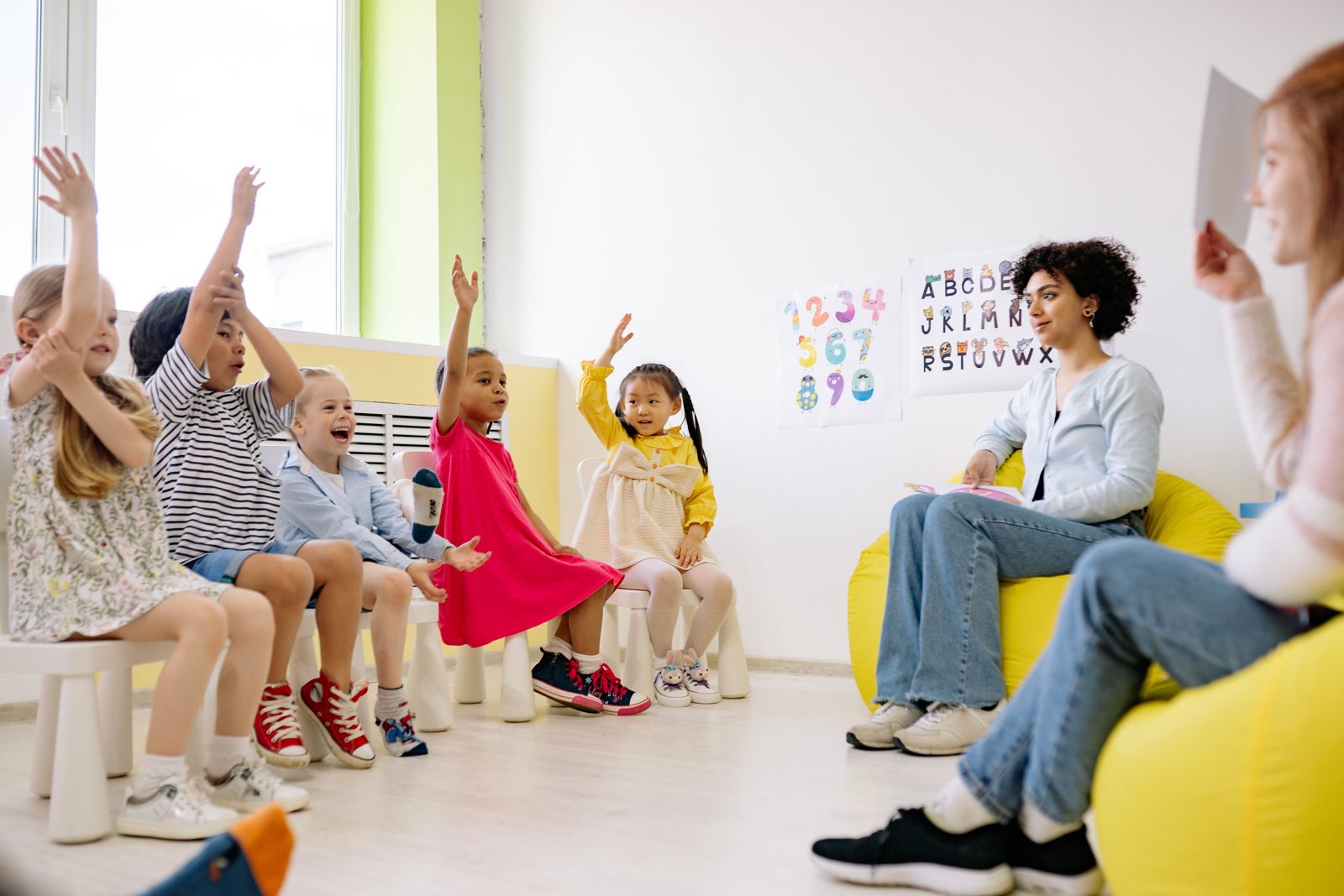 Children raising their hands during circle time at a child care program
