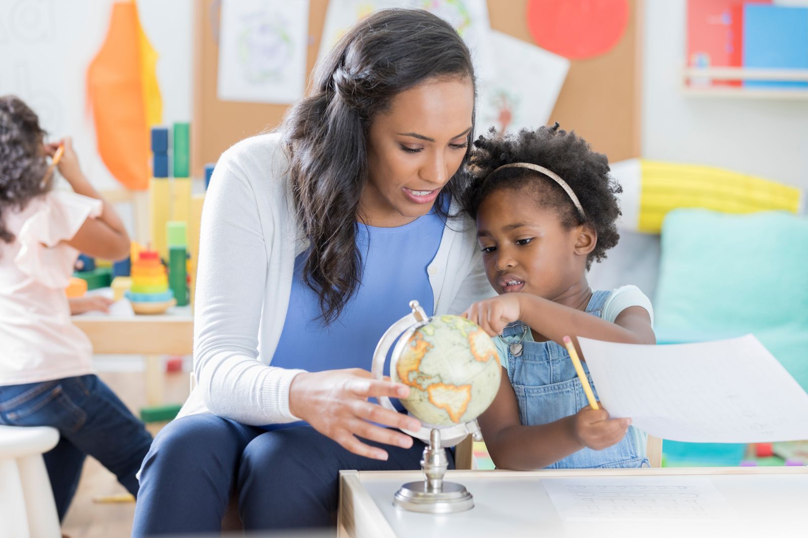 A teacher and a young child exploring a globe together